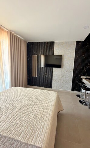 A hotel room with a bed, a mounted flat-screen TV, a bathroom with a sink, and a marble-patterned wall. - 🌴 Caribbean Resort-Style Paradise: Ocean Views, Pools, and Relaxation in Santa Marta (Santa Marta)