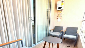 Ein Balkon mit einer Couch, zwei Stühlen und einem kleinen Tisch.