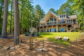 A large two-story house with a deck, surrounded by trees.