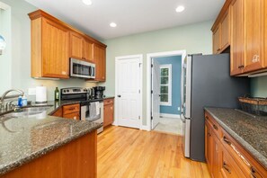 A kitchen with wooden cabinets, a microwave, a refrigerator, a sink, and a stove. - Lakin` It Easy | Fire Pit+H20 Trampoline+GameRoom (Henrico)