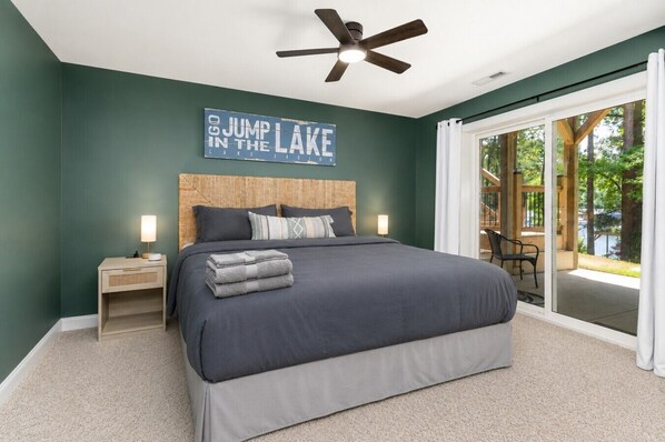 A bedroom with a bed, nightstands, a ceiling fan, a window with a view, and a sign on the wall.