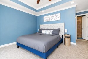 A bedroom with a bed, a nightstand, a wall clock, and a door leading to another room.