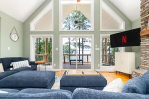 A spacious living room with a large couch, a coffee table, and a view of a deck with outdoor furniture.
