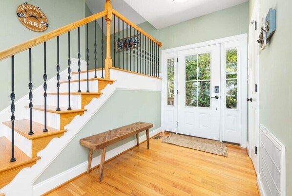 A staircase with wooden steps and black balusters, a bench, and a door with glass panels. - Lakin` It Easy | Fire Pit+H20 Trampoline+GameRoom (Henrico)