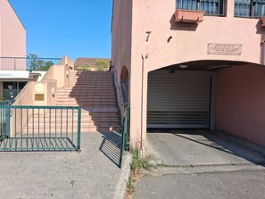 Um edifício com uma porta de garagem fechada, uma escadaria que leva ao segundo andar e uma placa indicando uma clínica médica.