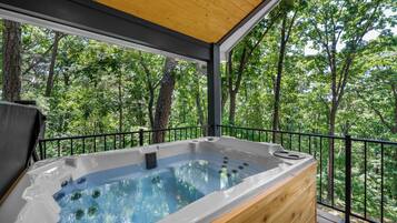 A hot tub on a deck with a forest view.