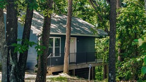 A cabin with a front porch, surrounded by trees. - Mountain Music Romantic Private Brow Cottage with Hot Tub (Fort Payne)