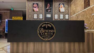 A reception desk with a logo for 'Beyond Limits Hotel' and a sign for 'Reception' in Arabic.