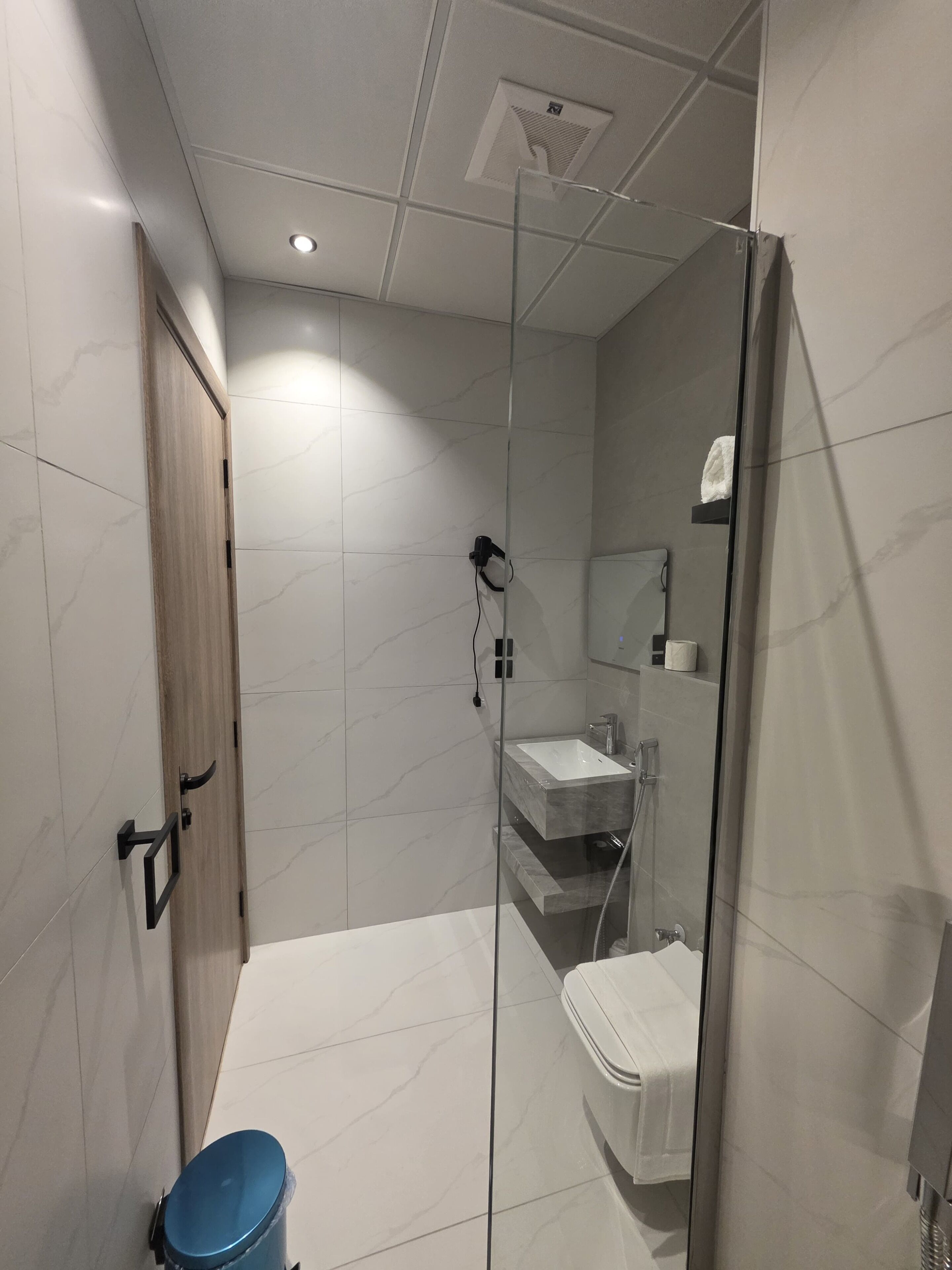 Un bagno moderno con doccia vetrata, lavandino bianco e servizi igienici.