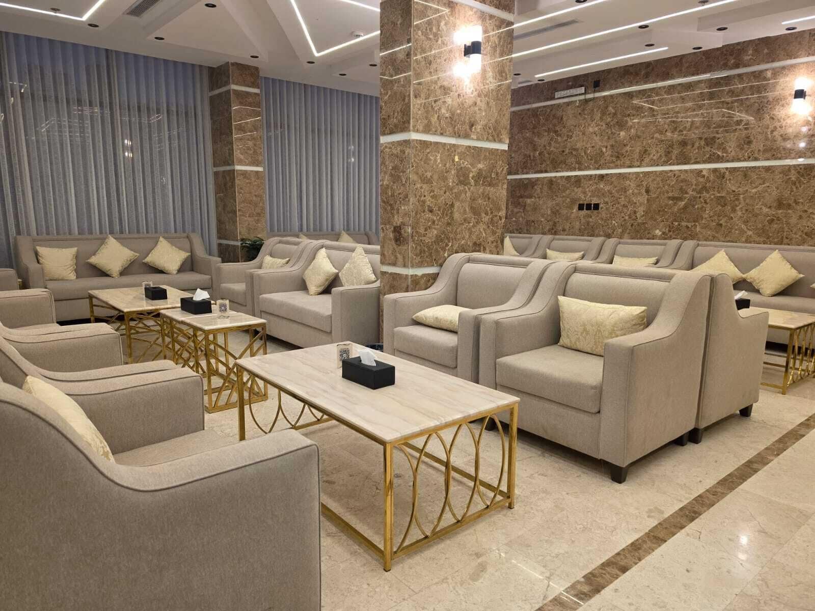 A modern lounge area with sofas and armchairs, a coffee table, and a marble floor.