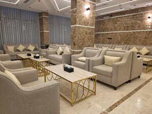 Un espace de détente moderne avec des canapés et des fauteuils, une table basse et un sol en marbre.