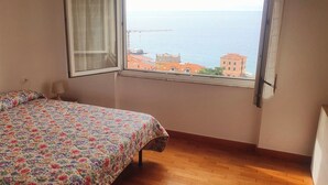 Ein Schlafzimmer mit einem Bett, einem Fenster und Blick auf Gebäude und Wasser.