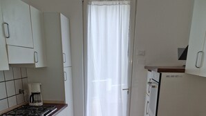 Eine Küche mit weißen Schränken, einer Holz Arbeitsplatte, einem Gasherd und einer Kaffeemaschine.