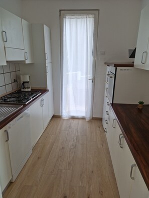 A kitchen with white cabinets, a wooden countertop, a gas stove, and a coffee maker. - detached villa in Varazze, sea view and private car parking space (Varazze)