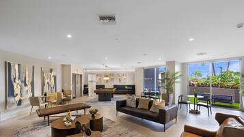 A spacious living area with a pool table, comfortable seating, and large windows offering a view of the outdoors.