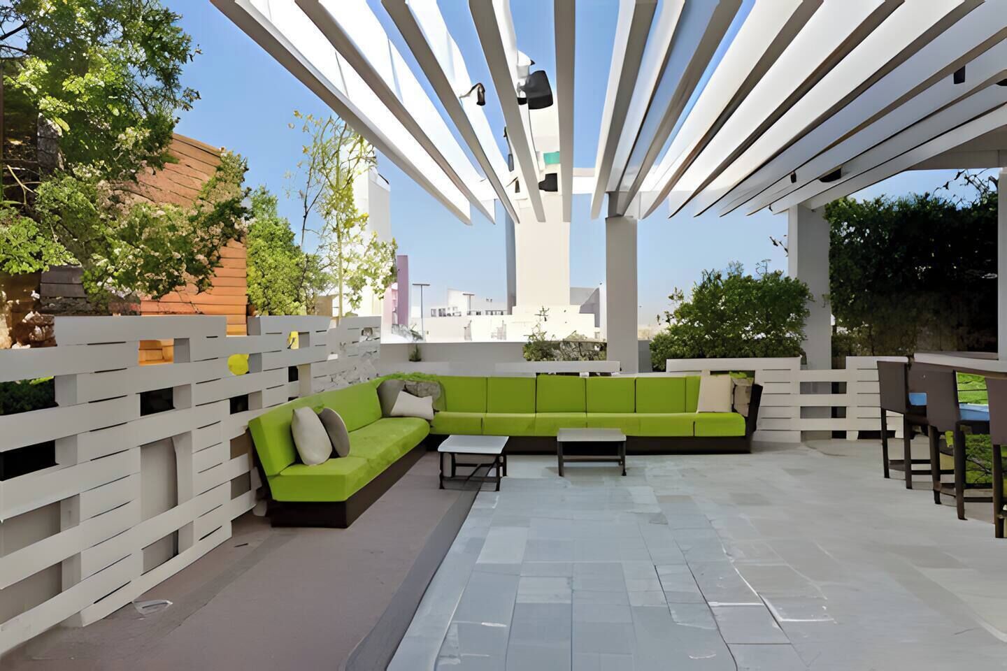 An outdoor seating area with a green sofa, white chairs, and a table.