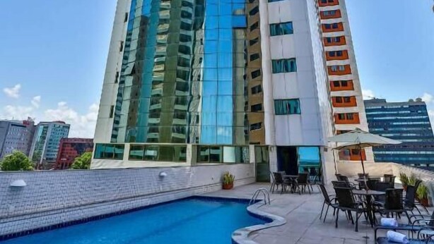 A high-rise building with a swimming pool and outdoor seating area.