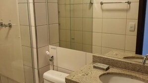 A bathroom with a toilet, a sink, a mirror, and a shower.