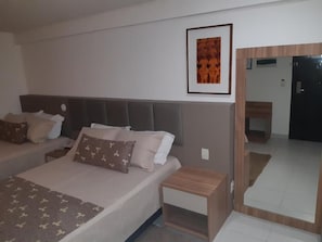 Ein Schlafzimmer mit einem Bett, Nachttischen, einem Spiegel und einem gerahmten Bild an der Wand.