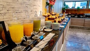 A buffet with various food items and drinks, including a fruit juice bar with labeled dispensers.