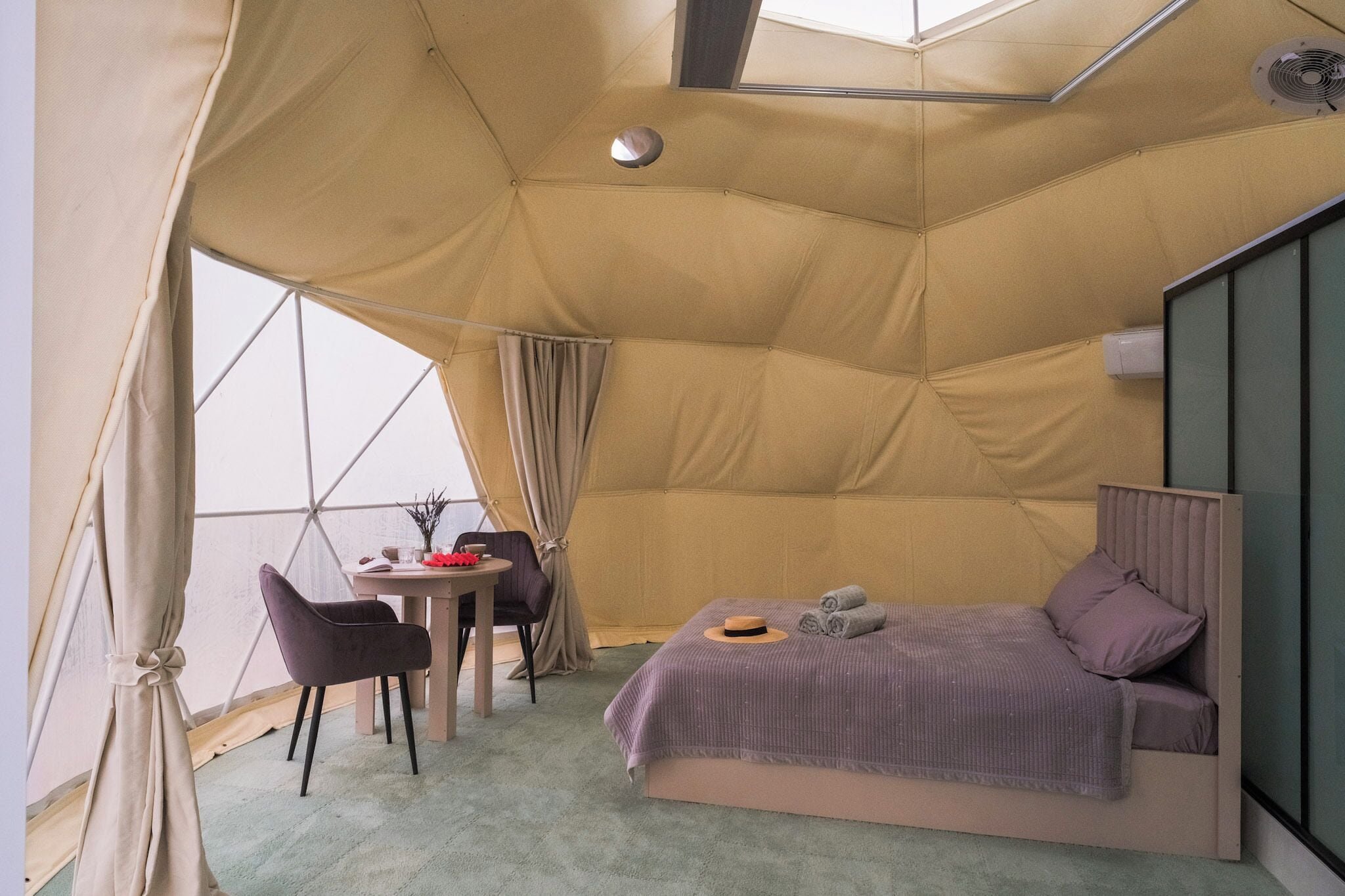 Una habitación tipo tienda de campaña con una cama, una mesa y sillas.