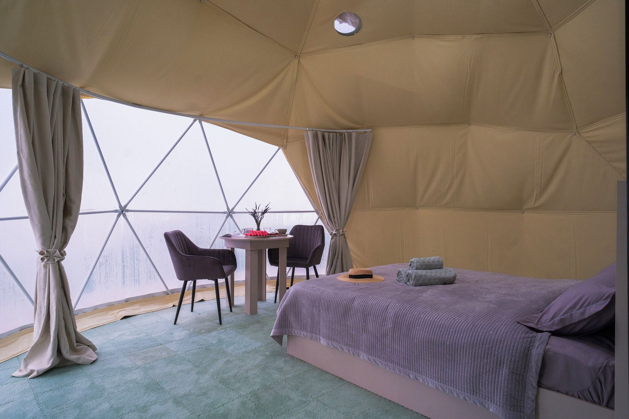 Una tenda-camera con un letto, due sedie, un tavolino e vista dalla finestra.