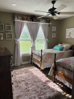 A bedroom with two beds, a ceiling fan, a fluffy rug, and a window with curtains. - Magnolia House In the Cove. Sweet Southern hospitality awaits you here. (Owens Cross Roads)