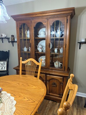 A dining area with a wooden table, chairs, and a china cabinet with glass doors.
