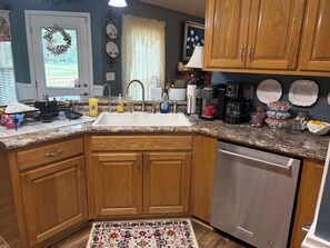 A kitchen with wooden cabinets, a stainless steel dishwasher, and a granite countertop.