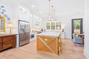 Una cocina amplia con armarios blancos, un refrigerador de acero inoxidable y una isla de madera.
