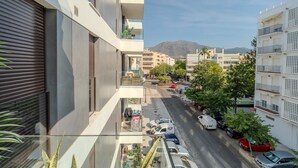 A modern building with a balcony, a street view, parked cars, and a mountain in the background. - Zaga3c - New Modern Apartment in Central Estepona (Estepona)