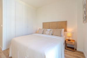 Ein Schlafzimmer mit einem großen Bett, einem Nachttisch mit Lampe und einem Kleiderschrank.