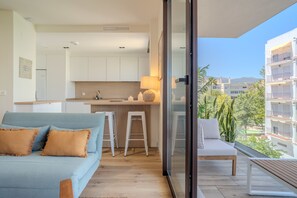 Eine moderne Wohnung mit Küchenzeile, einem Balkon mit Blick und einem Sofa.
