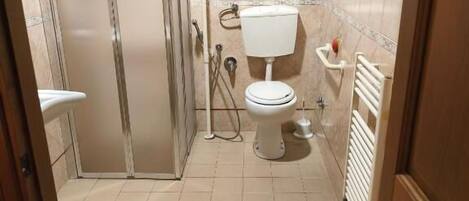 Baño con ducha, inodoro y radiador.