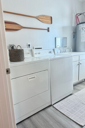 A laundry area with a washing machine, dryer, and a wooden paddle on the wall. - A Rare Bird:Spacious 5-bedroom, beachfront home in welcoming Gulf Shores with AC (Gulf Shores)