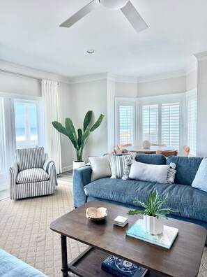 A living room with a sofa, armchair, coffee table, and a ceiling fan. - A Rare Bird:Spacious 5-bedroom, beachfront home in welcoming Gulf Shores with AC (Gulf Shores)