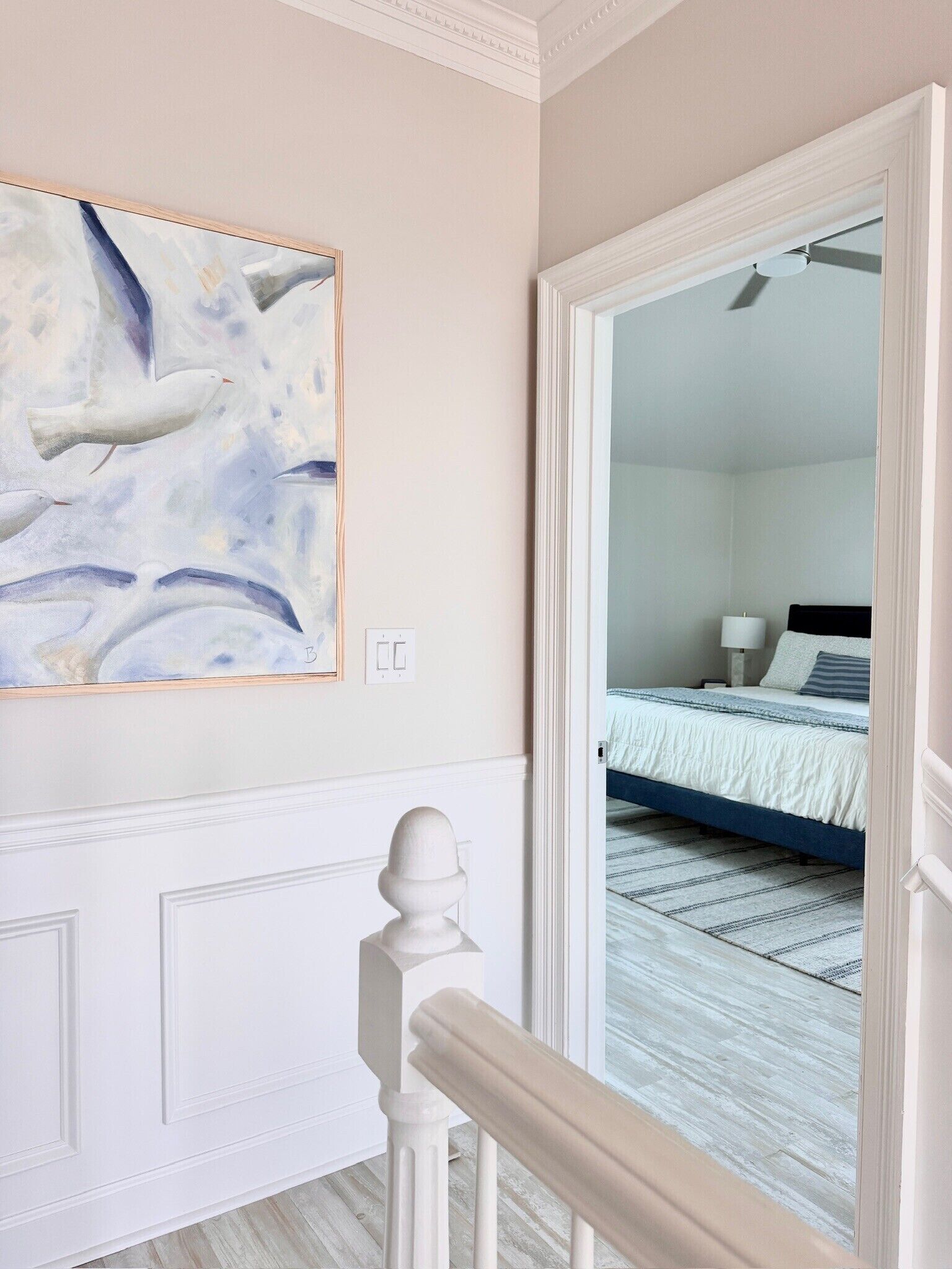 A bedroom with a bed, a bedside table, a lamp, and a painting on the wall.