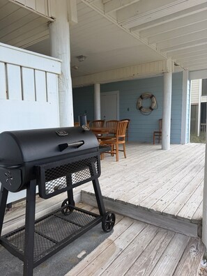 A covered outdoor area with a barbecue grill, wooden chairs, and a life ring on the wall. - A Rare Bird:Spacious 5-bedroom, beachfront home in welcoming Gulf Shores with AC (Gulf Shores)