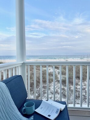 A view from a porch with a white railing, overlooking a beach with sand and sparse vegetation. - A Rare Bird:Spacious 5-bedroom, beachfront home in welcoming Gulf Shores with AC (Gulf Shores)