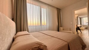 Ein Hotelzimmer mit einem großen Bett, einer Sitzecke und Blick ins Freie durch das Fenster.