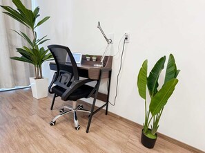 Ein moderner Arbeitsplatz mit Schreibtisch, Stuhl, Computer und zwei Blumentöpfen.