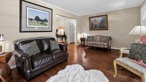 A living room with a leather couch, a patterned armchair, and a painting on the wall. - Peaceful Dallas Retreat Near Downtown & Fair Park (Dallas)