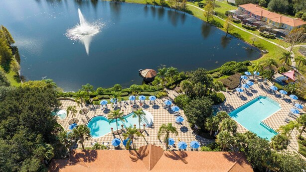 Ein Resort mit einem großen See im Zentrum, einer Springbrunnenanlage und mehreren Schwimmbecken mit Liegestühlen und Sonnenschirmen.