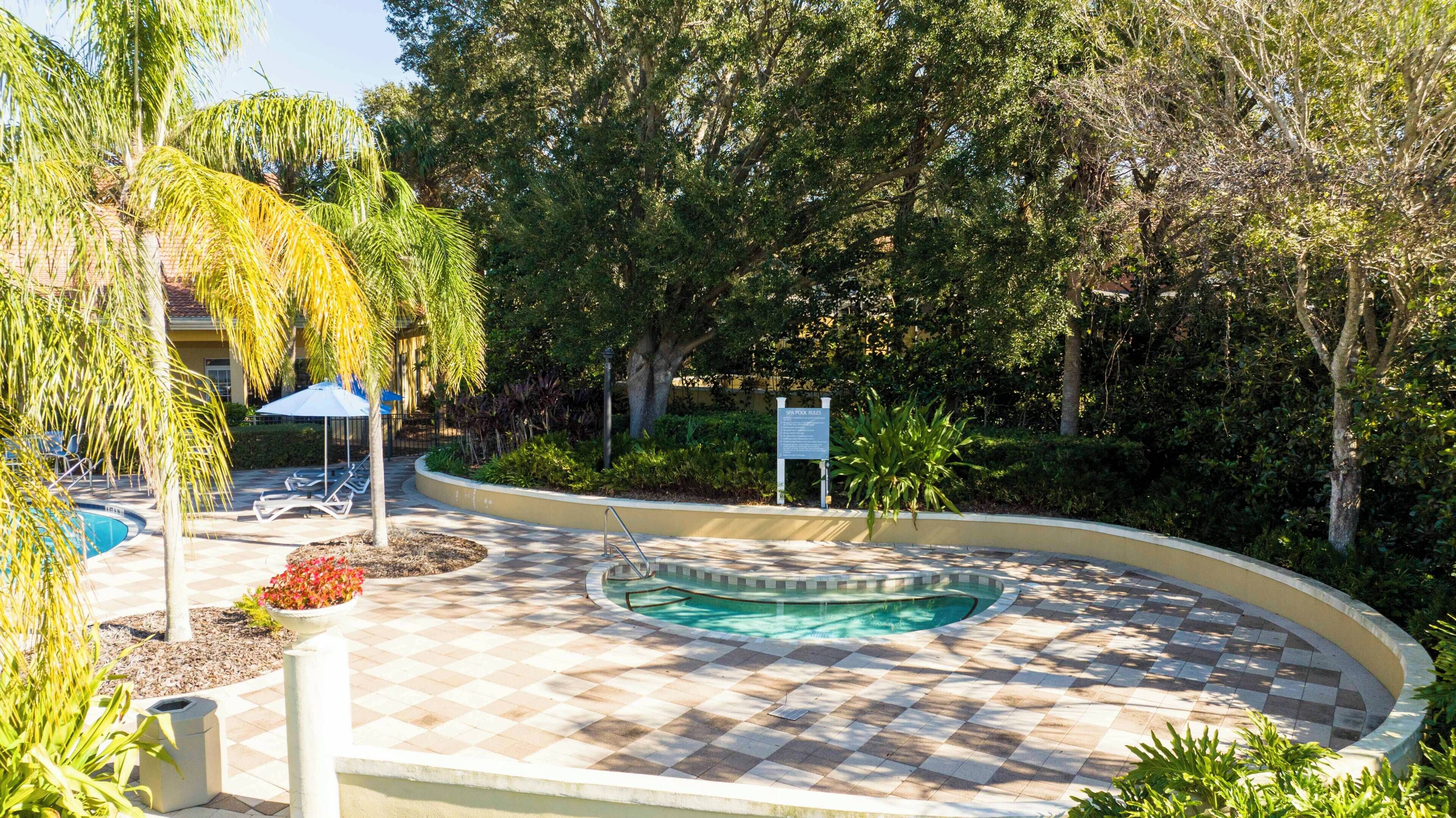 A pool area with a checkered pattern, lounge chairs, and a sign indicating pool rules.