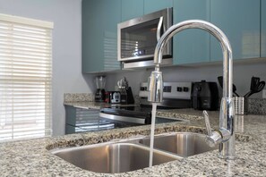 Una cocina con un lavamanos de acero inoxidable, un grifo moderno y encimeras de granito.