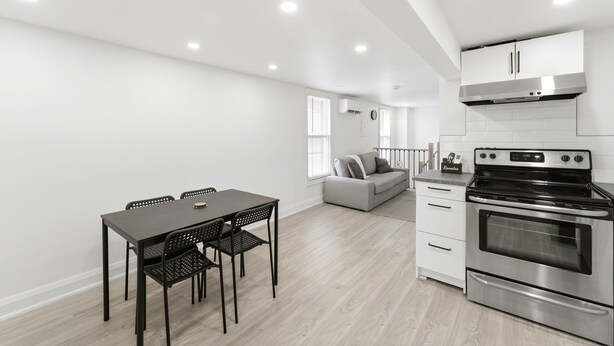 Een moderne keuken met een ingebouwde oven, een eettafel met stoelen en een bank op de achtergrond.