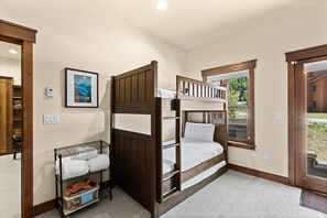 A bunk bed room with a window, a framed picture on the wall, and a door leading outside. - Perfect Family Getaway: 3BR with Hot Tub and Stunning Alpine Views (Keystone)