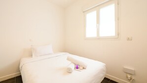 Ett hotellrum med en säng, ett fönster och ett eluttag på väggen.