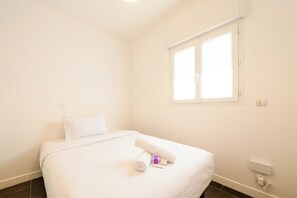 A hotel room with a single bed, a window, and a power outlet on the wall. - Quartz 5 Apartment (Cannes)