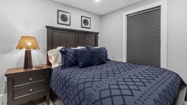 A bedroom with a bed, a nightstand, a lamp, and two wall-mounted pictures.